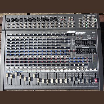 Šedý mixovací pult s nápisy SAMSON a 24 DSP. Pod logem je uveden model TXM80 1000W STEREO POWERED MIXER. Na ovládacím panelu jsou řady bílých a modrý…