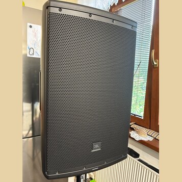 Černý aktivní reproduktor s kovovou mřížkou v horní a spodní části. V dolní části mřížky je umístěno logo JBL. Povrch přístroje i mřížka vykazují zná…