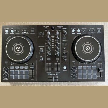 Černý DJ set tvořený dvěma kontrolérymi a centrálním mixérem. Na středovém panelu jsou nápisy PERFORMANCE CONTROLLER DDJ-400, rekordbox a Pioneer DJ.…