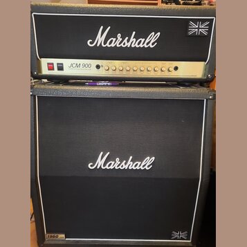 Kytarový zesilovač s boxem značky Marshall. Na hlavě je zlatý panel s nápisem JCM 900 a textem 100W SLP Gain/Bass Reflex Reverb, v pravém horním rohu…