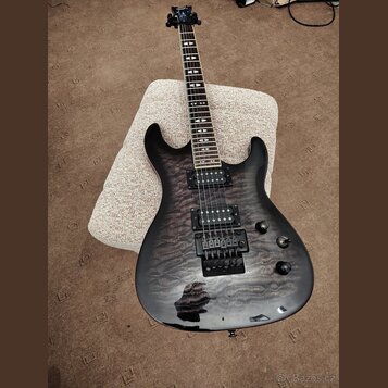 Černá elektrická kytara s výraznou strukturou dřeva na topu. Na hlavě hmatníku je viditelné logo PRS. Nástroj má dva humbuckery, prohýbatelný most a…