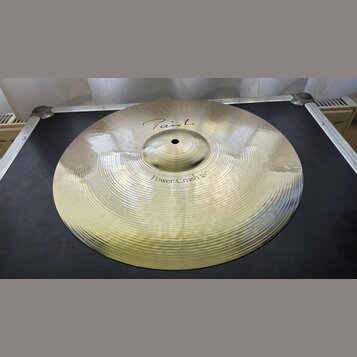Zlatavý kovový činel s viditelným rýhováním po celém povrchu. Na horní části je nápis "Paiste" a níže označení "Power Crash 16"". Povrch je čistý a b…