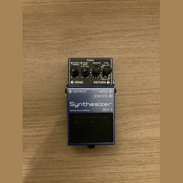 Modrý efekt pedál s nápisy Synthesizer a SY-1. Na horním panelu jsou dva černé otočné knoflíky s popisky RATE a DEPTH, přepínač EFFECT/DIRECT, TONE a…