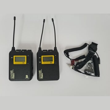 Dvě černé bezdrátové vysílačky s anténami a přiloženým kabelem s konektory. Na levém zařízení je nápis LENS 50, WIRELESS MICROPHONE TX a logo T.R. Sp…