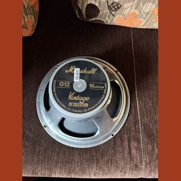Fotografie znázorňuje reproduktor s kovovým rámem a černým magnetem. Na zadní straně jsou nápisy „Marshall“, „G12“, „Vintage BY CELESTION“ a „16 ohms…