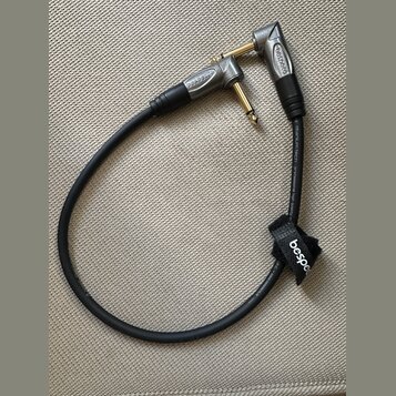 Černý instrumentální kabel s pozlacenými konektory a šedými kovovými kryty. Na obou konektorech i na černém suchém stahovátku je uveden nápis bespeco…