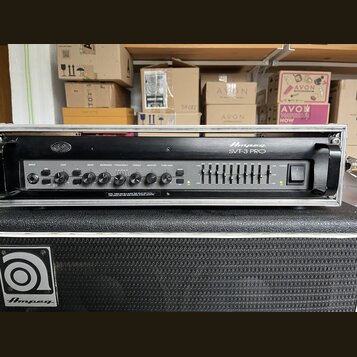 Černý basový zesilovač v kovovém šasi s nápisem Ampeg SVT-3 PRO. Přední panel obsahuje ovládací knofíky s popisky INPUT, GAIN, BASS, MIDRANGE, FREQUE…