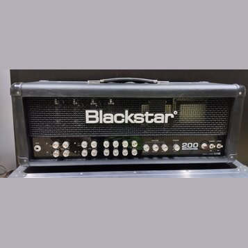 Černý kytarový zesilovač s kovovou mřížkou, na které je bílý nápis Blackstar. Přední panel obsahuje řadu ovládacích knoflíků a přepínačů s popisky ja…