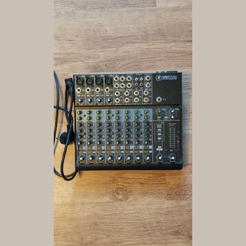 Mixovací pult s černým šasi a stříbrno-šedým horním panelem. V pravém horním rohu je logo značky a nápis 1202VLZ4 WITH ULTRA-LOW NOISE DESIGN. Zaříze…