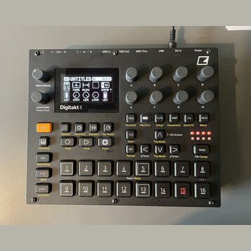 Černý sampler Digitakt II s displejem a řadou ovládacích prvků. Na přístroji jsou viditelná tlačítka, otočné knoflíky a v pravém horním rohu logo Ele…