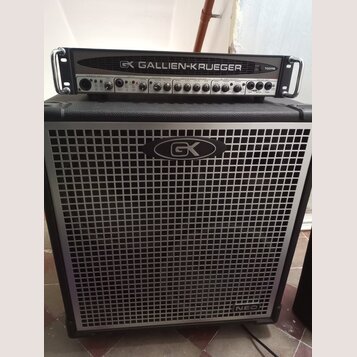 Černý basový zesilovač s hlavou a reproduktorovou skříní. Na hlavě je nápis GK GALLIEN-KRUEGER a označení modelu 700RB. Přední mřížka skříně je stříb…