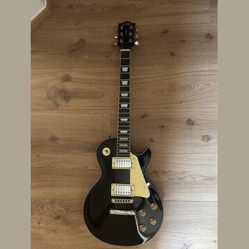Černá elektrická kytara s tvarem typu Les Paul a krémovým pickguardem. Na hlavě hmatníku je bílý nápis Era. Nástroj má dva humbuckery s krémovými rám…