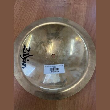 Kulatý mosazný činel s logem Zildjian. Na povrchu je nalepená bílá štítková nálepka s čárcovým kódem a textem ZILDJIAN 9-5" 24 bell large A20002 pouz…