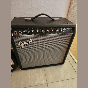 Černý kytarový kombo zesilovač s šedou síťovinou. Na předním panelu je nápis Fender a v pravém horním rohu označení Champion 40. Ovládací panel obsah…