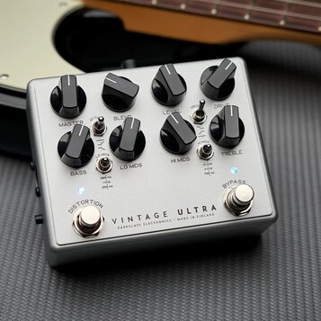 Stříbrný efekt pedál s osmi černými ovládacími knoflíky. Na spodní části je nápis VINTAGE ULTRA a pod ním menším písmem DARKGLASS ELECTRONICS - MADE…
