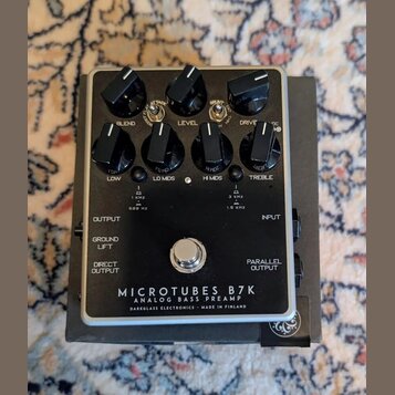Černý basový předzesilovač v kovovém šasi s nápisy MICROTUBES B7K, ANALOG BASS PREAMP a DARKGLASS ELECTRONICS - MADE IN FINLAND. Zařízení má sedm čer…