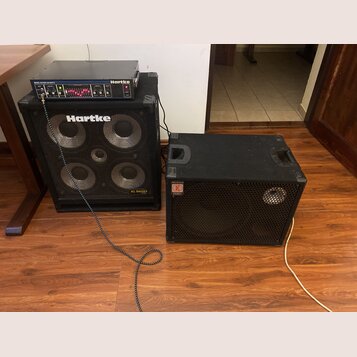 Na fotografii jsou dvě basové komba v černém provedení. Levý set tvoří zesilovač s nápisem Hartke a MODEL 400XL 400 WATTS umístěný na boxu s logem Ha…