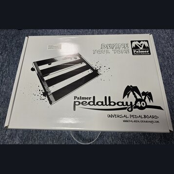 Bílá papírová krabice s černými nápisy a grafikou. Na povrchu je obrázek pedalboardu a texty „DEFINE YOUR TONE“, logo „Palmer Musical Instruments“ a…