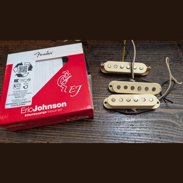Sada tří kytarových snímačů v krabici s nápisy Fender, Eric Johnson a STRATOCASTER PICKUP SET. Snímače jsou krémové barvy s viditelnými bílými magnet…