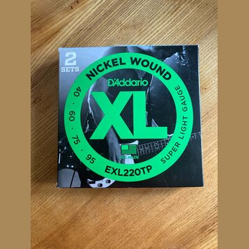 Krabice s dvěma sadami strun s nápisy NICKEL WOUND, D'Addario a XL. Na obalu je dále uveden model EXL220TP, označení SUPER LIGHT GAUGE a hodnoty 40,…