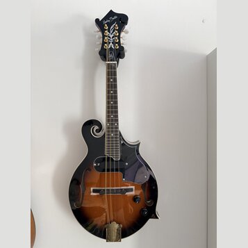 Černá mandolina s tělem v přechodové hnědo-černé barvě (sunburst) a f-otvory. Na hlavě je bílý nápis Harley Benton a dekorativní ornament. Nástroj má…