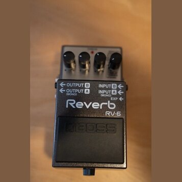 Kytarový efekt pedál značky BOSS, model RV-6 Reverb. Zařízení má černé kovové šasi s bílými nápisy OUTPUT B, OUTPUT A (MONO), INPUT B, INPUT A (MONO)…