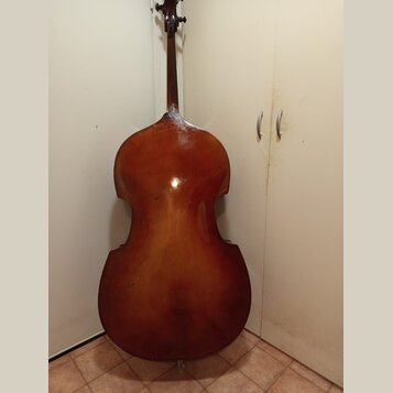 Fotografie zachycuje zadní stranu smyčcového nástroje, pravděpodobně violoncella, v hnědém lakovaném provedení. Nástroj je vyroben ze dřeva a vykazuj…