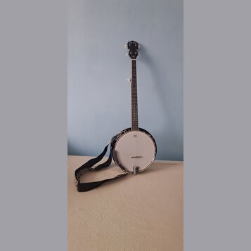 Černý banjo s bílou membránou a kovovým rímcem. Na hlavě hředu je viditelně nápis „Ruby Pearl“. K nástroji je přiložen černý popruh s bílým vzorem.