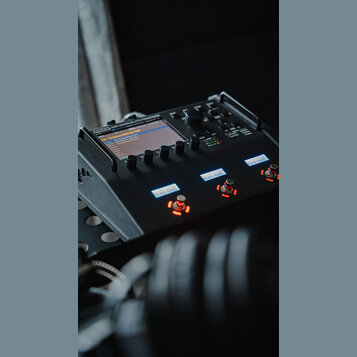 Černý kytarový procesor s nápisem FM3 AMP MODELER / FX PROCESSOR. Zařízení má digitální displej, několik ovládacích knoflíků a tři podsvícená tlačítk…