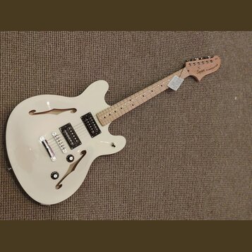 Bílá polodublová elektrická kytara s přírodním hřidlem a hlavou. Na hlavě je nápis "Squier STARSCASTER". Tělo má dva humbuckery, dva ovládací knoflík…