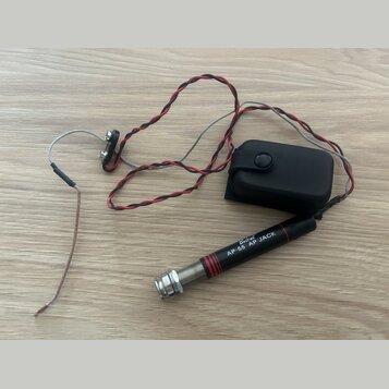 Černý kabel s červenými vodiči a stříbrným opletením, který končí v konektoru s nápisy „Belcat“ a „AP-55 AP JACK“. Součástí je černý plastový box s t…