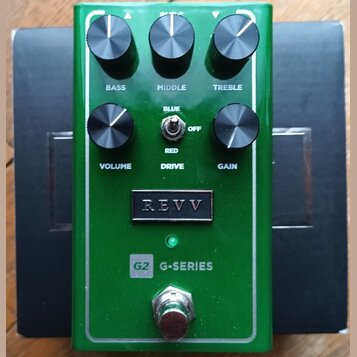 Zelený kytarový efekt s pětí knoflíky a přepínačem. Na přístroji jsou nápisy BASS, MIDDLE, TREBLE, VOLUME, GAIN a DRIVE s přepínačem označeným BLUE,…