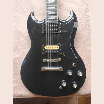 Černá elektrická kytara s dvěma humbuckery, z nichž jeden má zlatý kryt. Na těle jsou čtyři ovládací knofíky a přepínač tónu. Povrch laku vykazuje dr…