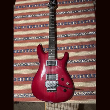 Elektrokytara s červeným lakovaným tělem a hnědým hnedým hmatníkem. Na hlavě je bílé logo Ibanez a na krku nápis RG 5220. Kytara má dva humbuckery, t…