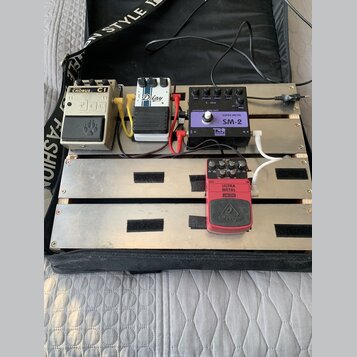 Kytarový pedalboard v černém přepravním kufru s několika efekty. Jsou zde pedály s nápisy CHORUS C1, Delay a ULTRA METAL UM300 od značky behringer. V…
