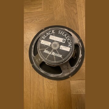 Kytarový reproduktor s černým rámem a membránou. Na středovém štítku je uveden nápis BLACK SHADOW, logo CELESTION INTERNATIONAL a značka Mesa/Boogie.…
