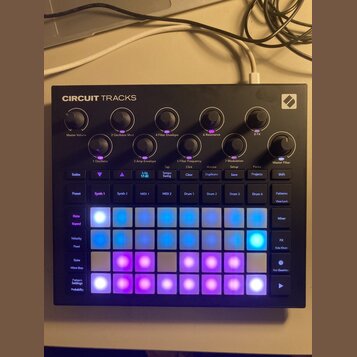 Černý sekvenční syntetizátor s nápisem CIRCUIT TRACKS a logem Novation v pravém horním rohu. Zařízení obsahuje řadu otočných potenciometrů s označení…
