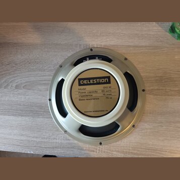 Fotografie zachycuje zadní stranu reproduktoru s krémovým rámem a magnetem. Na štítku je uveden nápis CELESTION a specifikace: Model G12 M, Power cap…