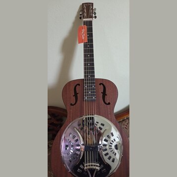 Hnědá akustická kytara typu resonator s kovovým, chromovaným krytem v těle. Na hlavě hředu je bílý nápis Harley Benton a na krku visí oranžová visačk…