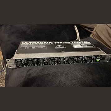 Stříbrný rackový přístroj s černým horním panelem. Na vrchu je bílý nápis ULTRAGAIN PRO-8 Digital a PROFESSIONAL 8-CHANNEL A/D & D/A CONVERTER MODEL…