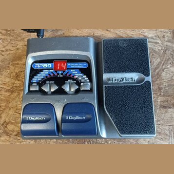 Šedý kytarový procesor Digitech RP80 Modeling Guitar Processor s integrovaným expresním pedálem. Zařízení má digitální displej zobrazující červenou č…