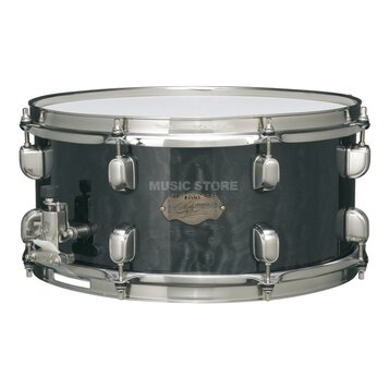 Černý snare drum s kovovým obručováním a chromovaným mechanismem. Na koruse je zlatý oválný štítek s nápisy „TAMA“, „Custom Superior“ a podpisem, kte…