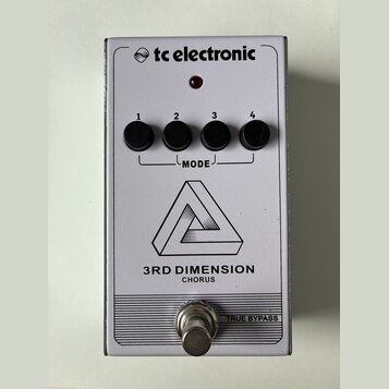 Bílý kytarový efekt s nápisem tc electronic a označením 3RD DIMENSION CHORUS. Na horní straně jsou čtyři černé otočné ovladače s čísly 1 až 4, které…