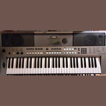 Šedý elektronický klavír s bílými a černými klávesami. Na horní části je uprostřed logo YAMAHA, displej a po obou stranách mřížkovité reproduktory. V…