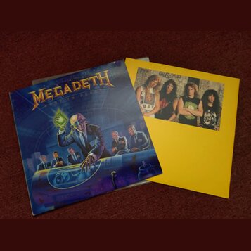 Fotografie zobrazuje obal CD a doprovodný žlutý vložkový papír s fotografií kapely. Na obalu je nápis MEGADETH a pod ním text RUST IN PEACE, doprováz…