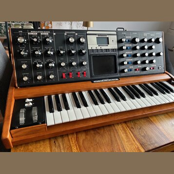 Synthesizér s klaviatura v dřevěném šasi. Na horním ovládacím panelu jsou nápisy LFO, MODULATION BUSSES, OSCILLATORS, MIXER, FILTERS, ENVELOPES a OUT…