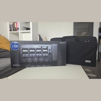 Krabice s nápisem ZOOM G5n Multi-Effects Processor a doprovodný černý polstrovaný pouzdro. Na krabici je vidět obrázek efektového procesoru a modrý š…