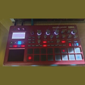 Červený sampler KORG electribe sampler MUSIC PRODUCTION STATION. Zařízení obsahuje displej s nápisem 001 Advisory 1 Part: 16 OSC Ride Hummy, několik…