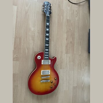 Elektrická kytara s červeným sunburst povrchem a tvarem Les Paul. Na hlavě hředu je bílý nápis Epiphone. Nástroj má dva humbuckery, čtyři otočné knof…
