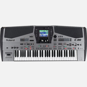 Stříbrný digitální klavír s černými mřížkovými panely v horní části. Na levé straně je nápis Roland a na pravé straně označení E-80 MUSIC WORKSTATION…